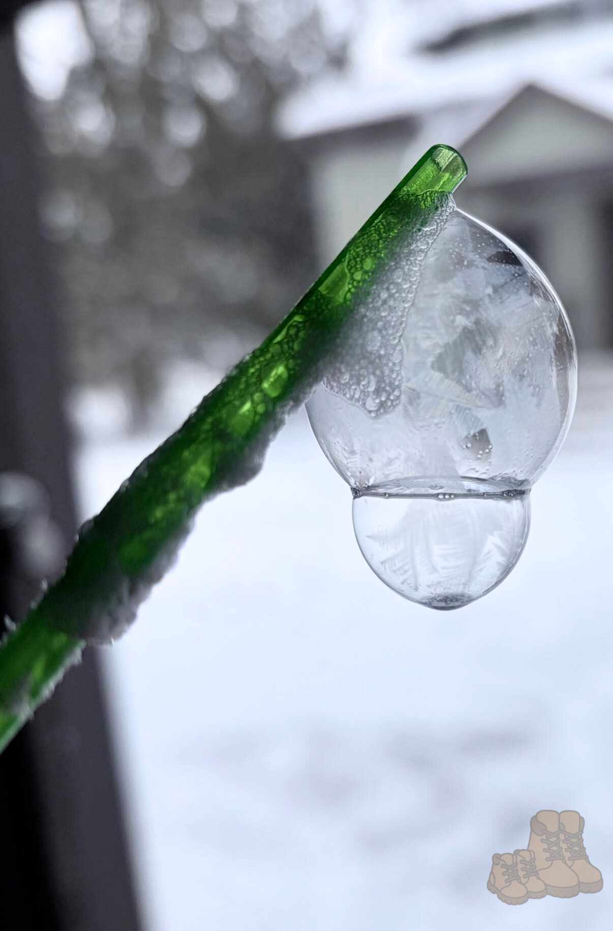 A bubble with ice formations suspended on a green straw